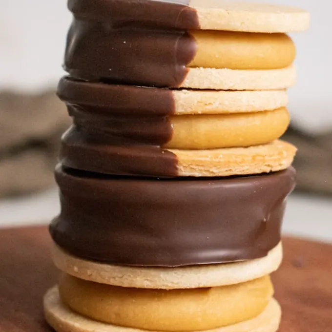 Stack of classic vegan alfajores half-dipped in dark chocolate